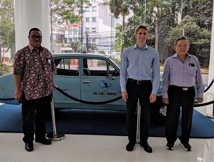 People standing in front of a blue car