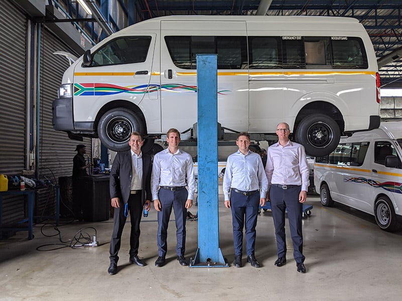 Four people standing in front of a minibus