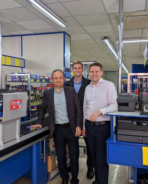 Three men standing at Lidl check out aisle