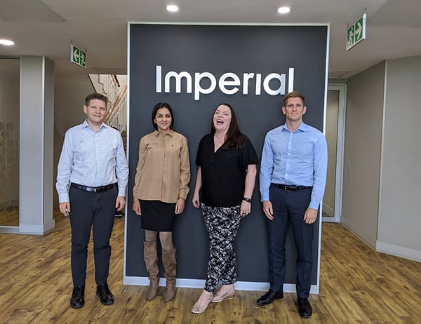 People standing in front of a Imperial- logo in an office