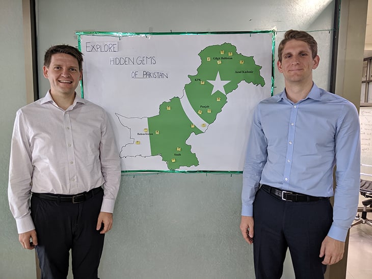 Two men standing in front of a pakistanian map