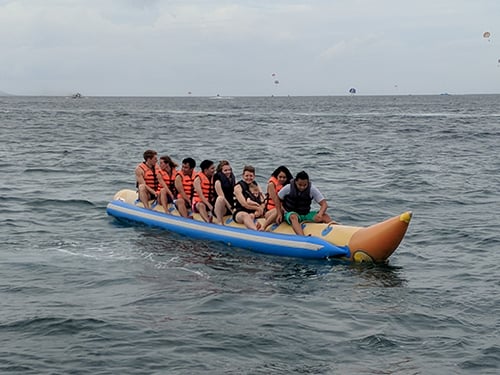 People sitting on top of a banana-shaped floating device in water.
